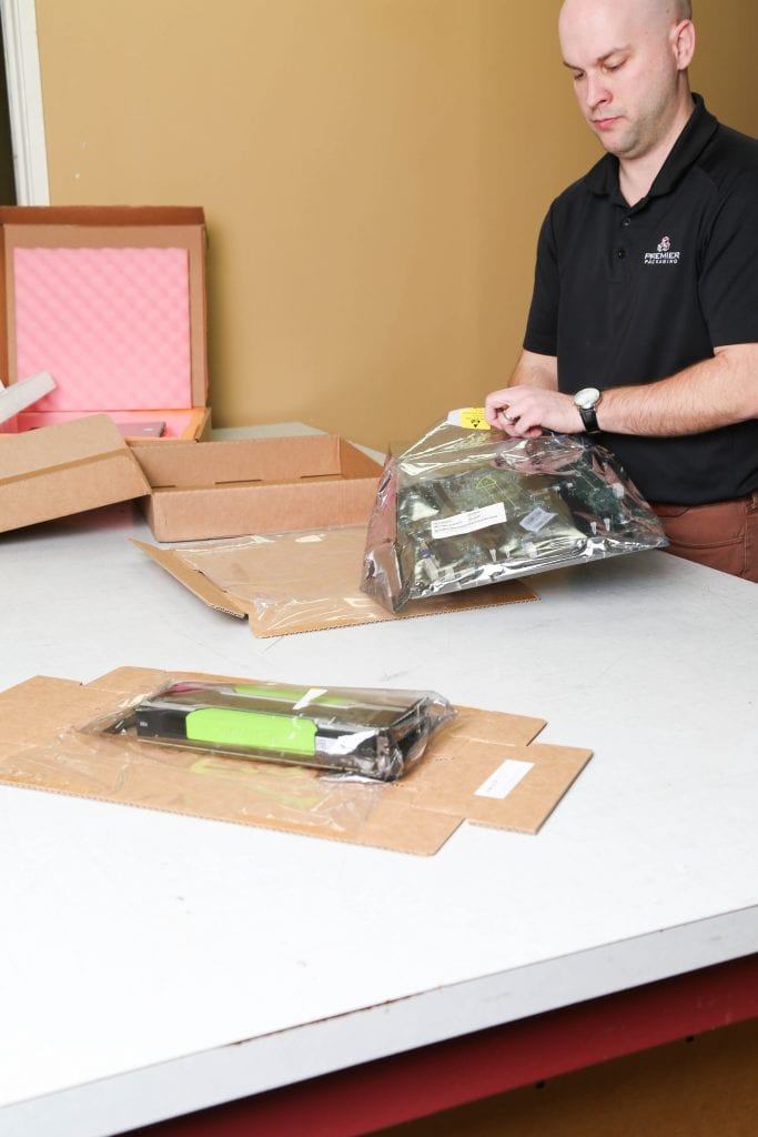 Premier Packaging employee packing a circuit board; protective packaging; electronic packaging; premier protective packaging