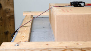 Package strapped to vibe table to undergo ISTA-certified testing