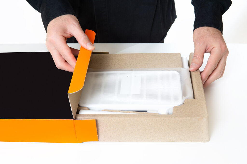 Man unboxing new electronic inside corrugated box with protective packaging; electronic packaging; premier protective packaging