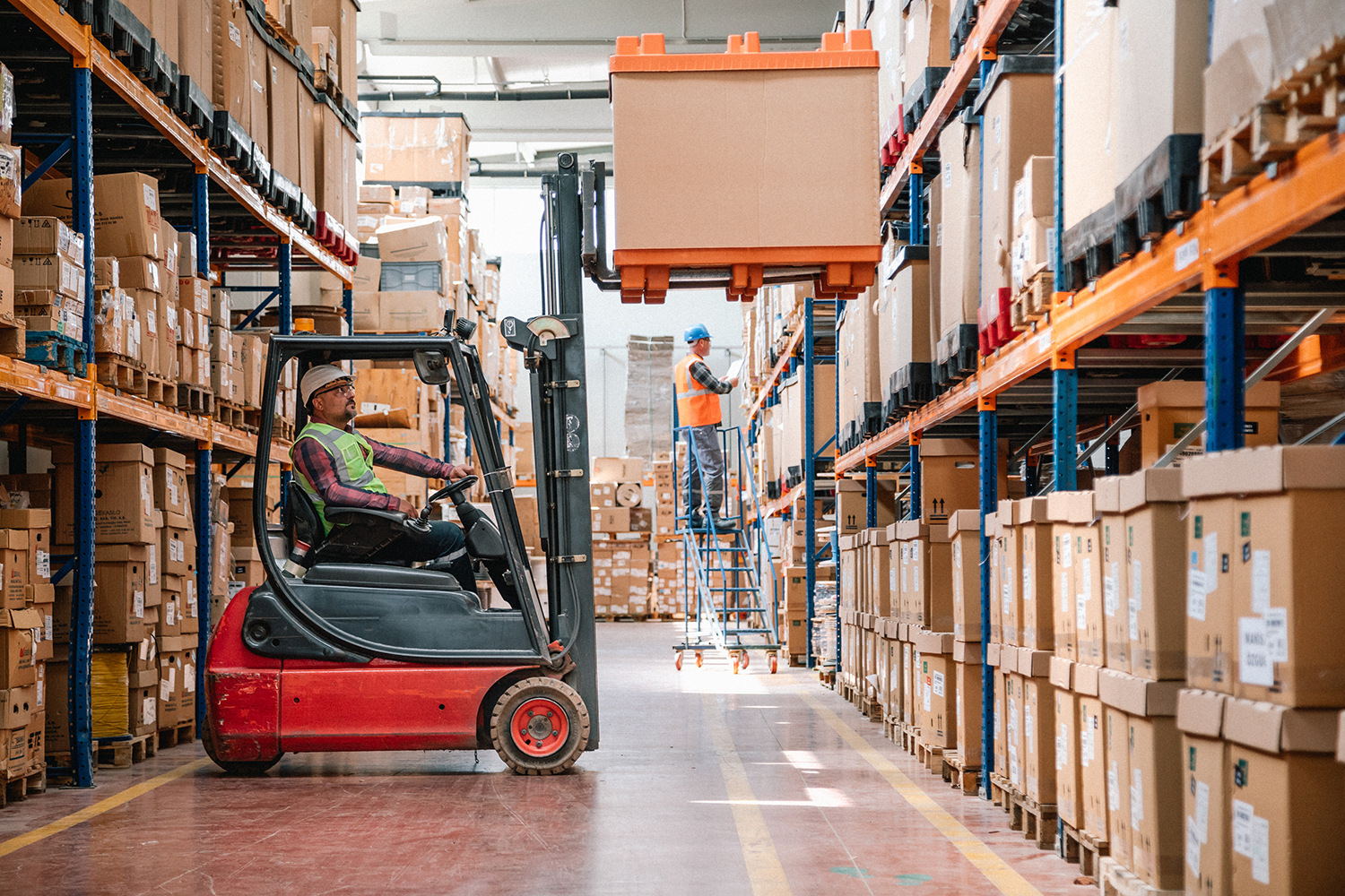 Warehouse Using Loading Tools Uniformed Worker Driving and Loading corrugated boxes in a warehouse ...