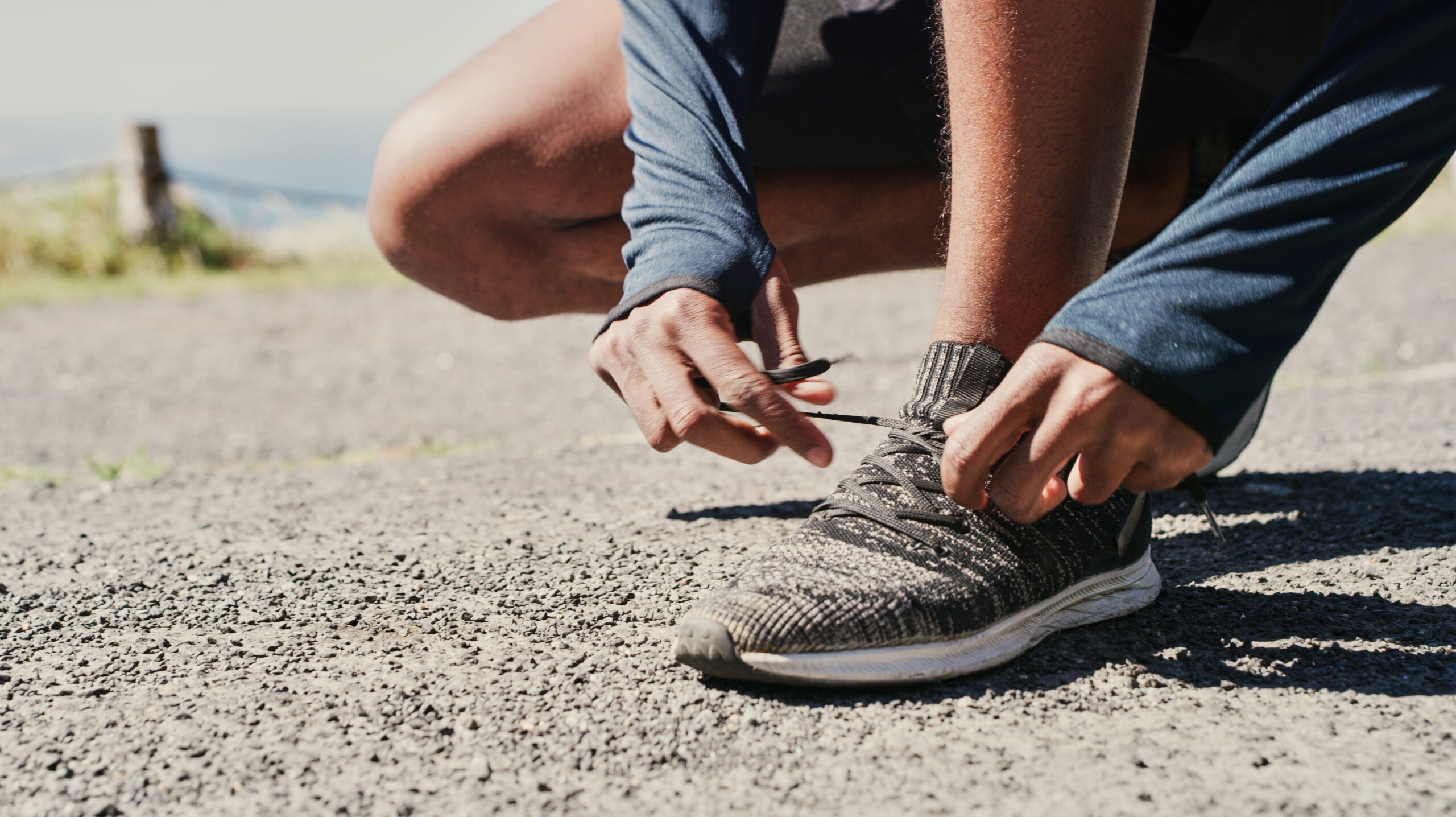 Foto recortada de hombre atándose los cordones para salir a correr.