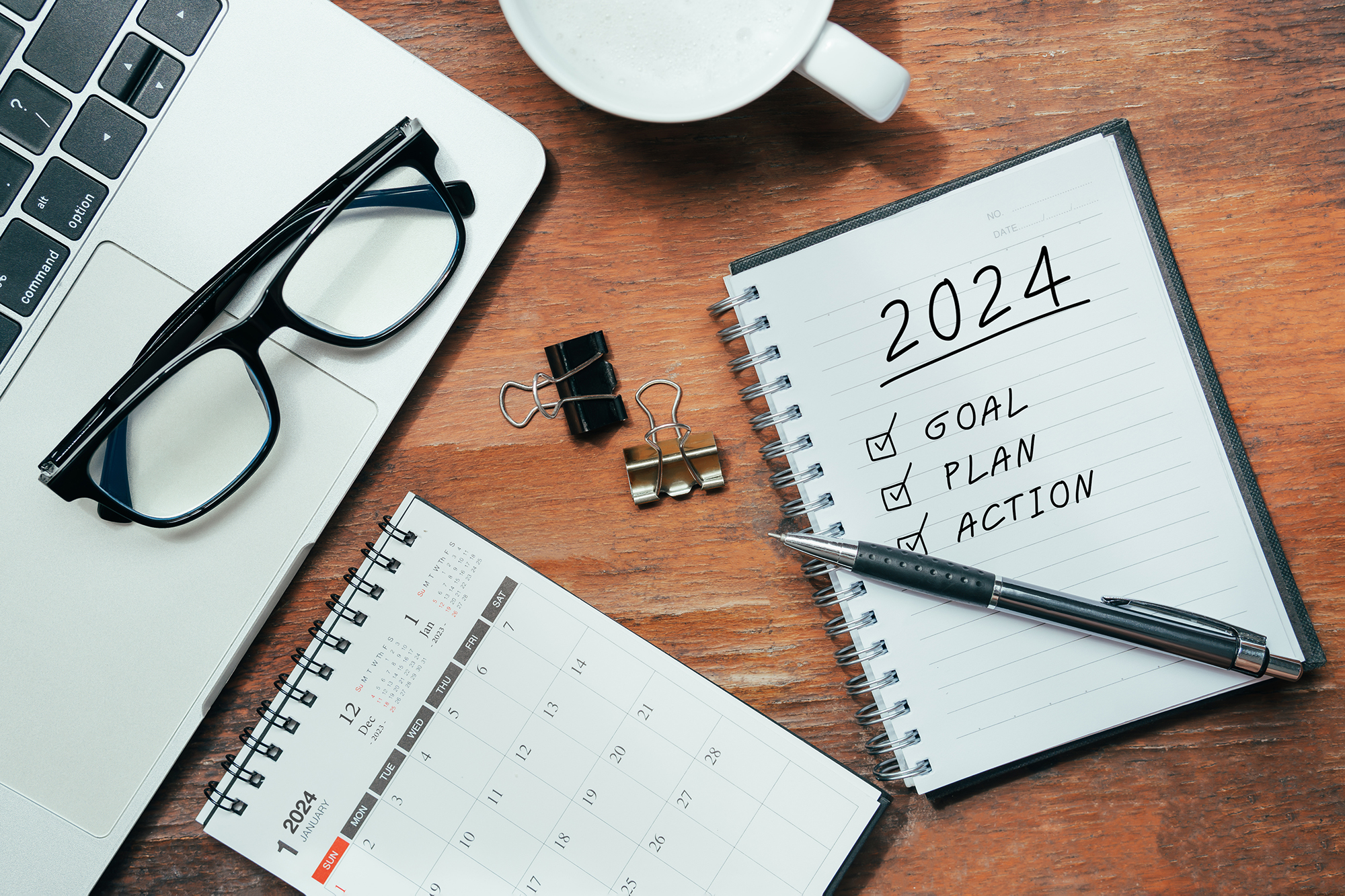 New Year's resolutions 2024 on wooden table. Goals, plans and action ideas for New Year 2024. Notebook with fingerprints. Coffee cup on table, goal, resolution, plan, action, checklist concept