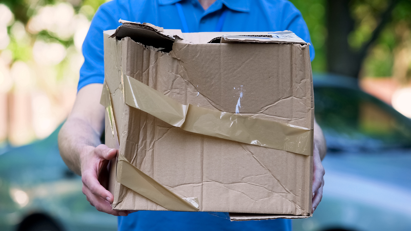 Mensajero que muestra una caja dañada, entrega de paquetes barata, mala calidad de envío