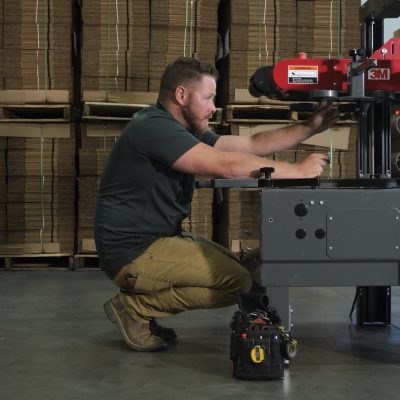 Case Sealer Machine being serviced Premier Packaging employee services a case sealer machine; Technician servicing machine; Equipment Servicing; Equipment maintenance; Preventative maintenance; packaging for brands