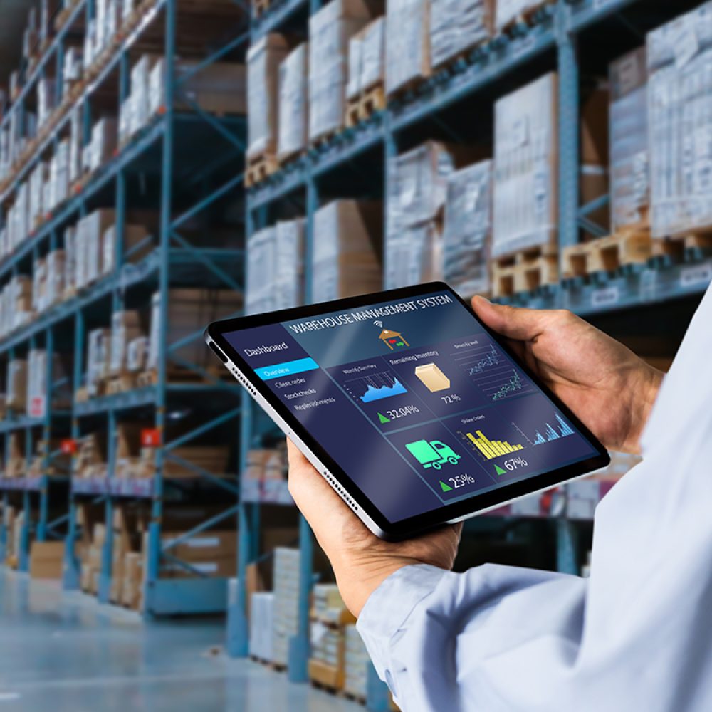 Manager using digital tablet,showing warehouse software management dashboard on blurred warehouse as background