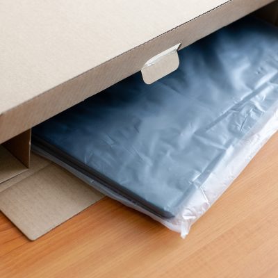 Unpacking new blue laptop at wooden desk; packaging industries
